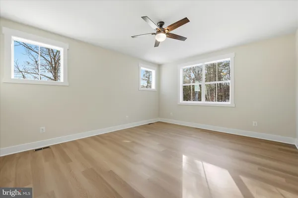 a view of empty room with wooden floor and fan