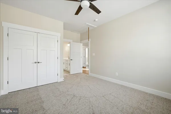 an empty room with chandelier fan and closet