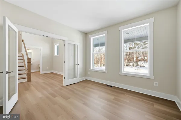 an empty room with wooden floor cabinet and windows