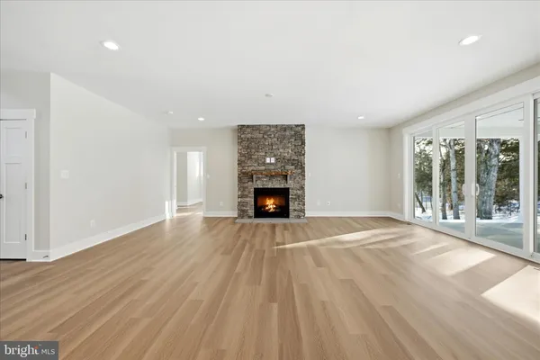 a view of an empty room with wooden floor fireplace and a window