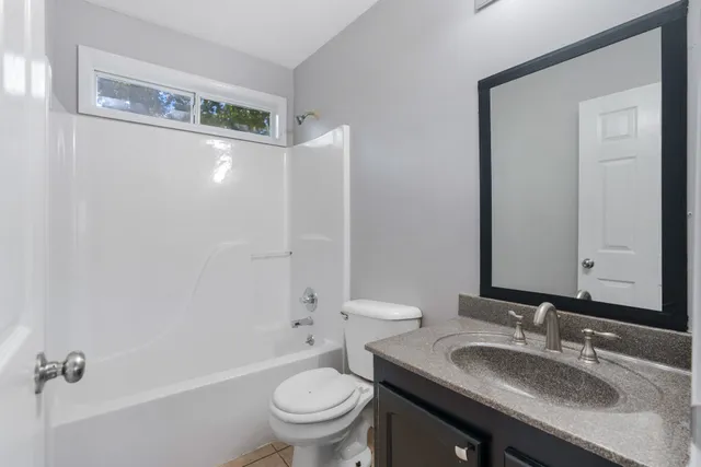an empty room with ceiling fan and windows