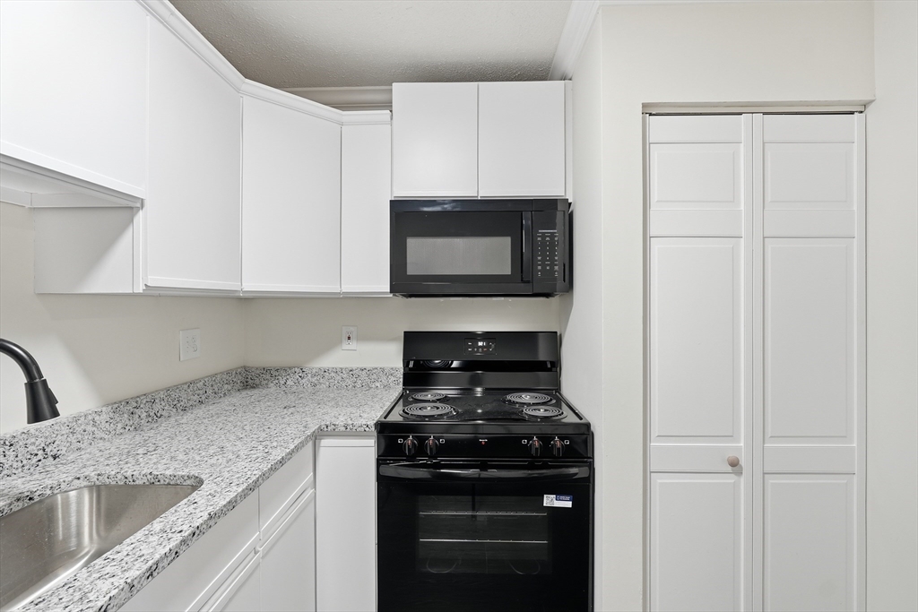 30 Abbey Road, Unit 102 Leominster, MA 01453 - Photo 9 of 15 a kitchen with granite countertop white cabinets and black appliances