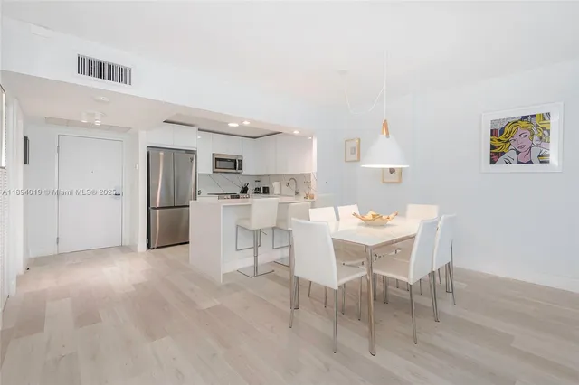 a kitchen with stainless steel appliances a table and chairs in it