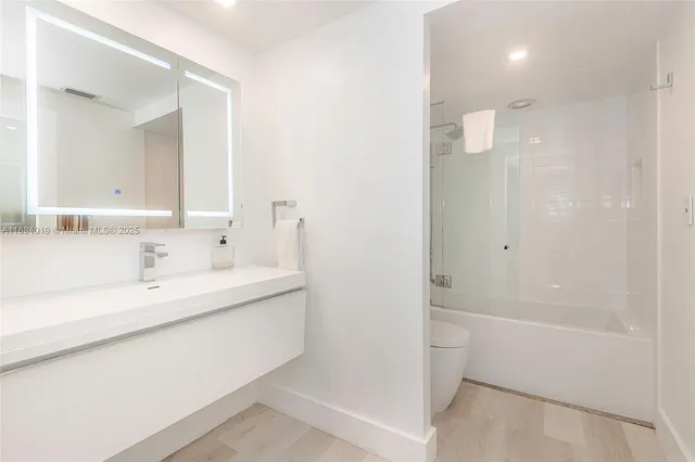 a bathroom with a granite countertop sink a toilet and shower