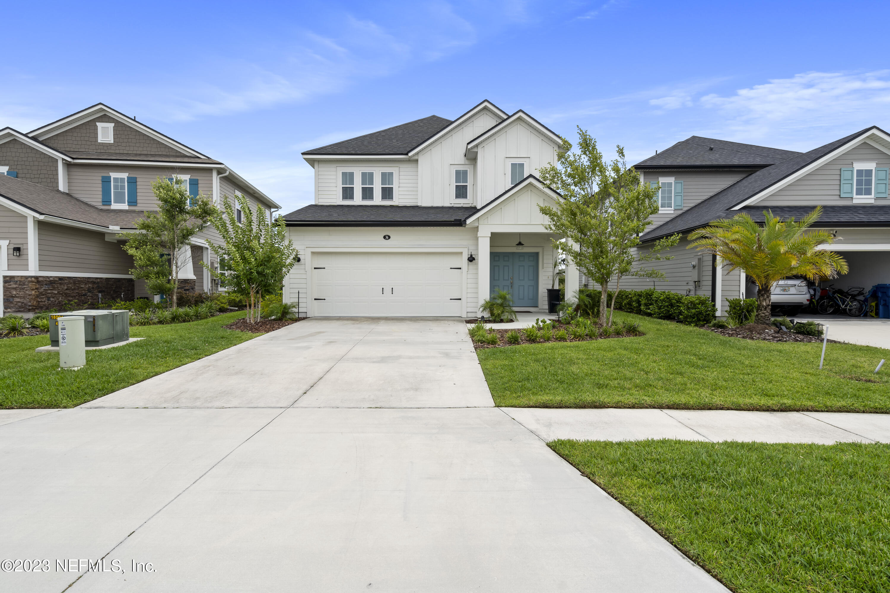 a front view of a house with a yard and potted plants
