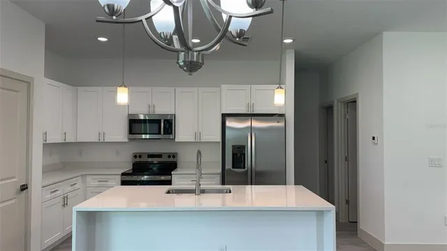a kitchen with a sink stainless steel appliances a refrigerator and cabinets