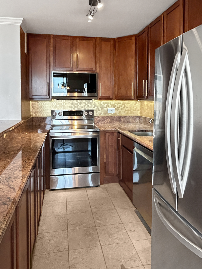655 West Irving Park Road, Unit 3608 Chicago, IL 60613 - Photo 5 of 20 a kitchen with stainless steel appliances granite countertop a stove microwave and refrigerator