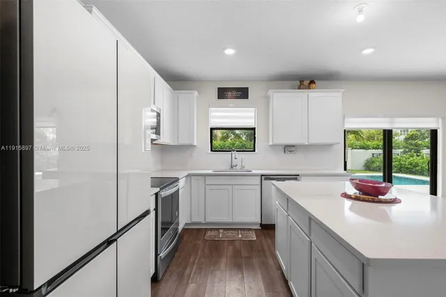 a kitchen with a sink cabinets stainless steel appliances and windows