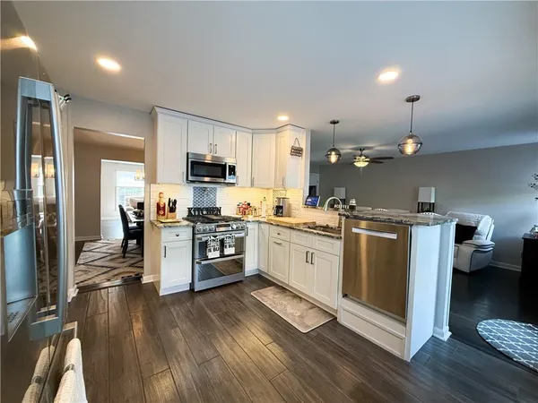 a kitchen with granite countertop a refrigerator oven a sink dishwasher and a stove with wooden floor