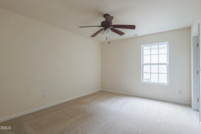 an empty room with a ceiling fan and a window