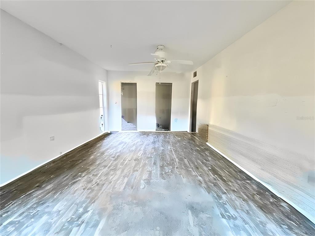 4832 Jasper Drive, Unit 107 New Port Richey, FL 34652 - Photo 11 of 27 an empty room with wooden floor and ceiling fan