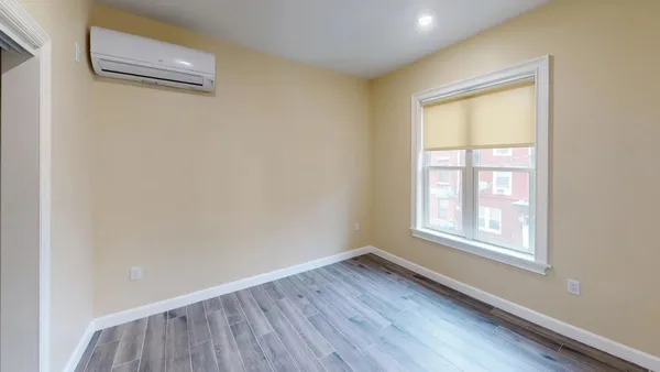 an empty room with wooden floor and windows