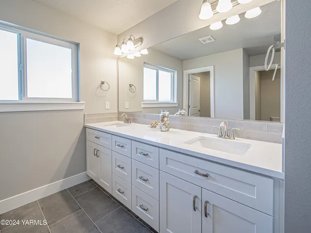 a bathroom with double sink large mirror and a vanity