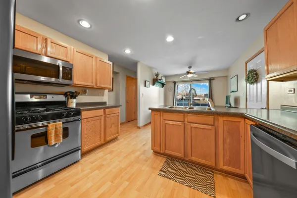 a large kitchen with stainless steel appliances granite countertop a stove a sink and a microwave