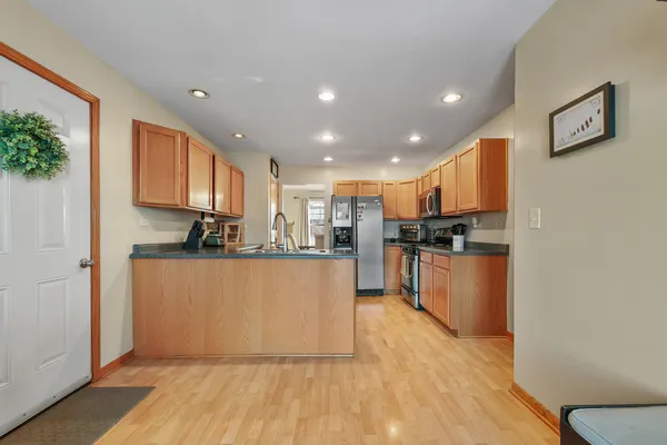 a view of kitchen with stainless steel appliances granite countertop a stove top oven a refrigerator a sink and dishwasher with wooden floor