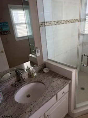 a bathroom with a granite countertop sink and shower