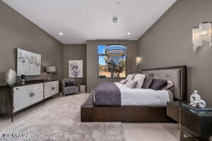 1313 Tortolita Mountain Circle Tucson, AZ 85755 - Photo 32 of 46 a spacious bedroom with a large bed and a chandelier