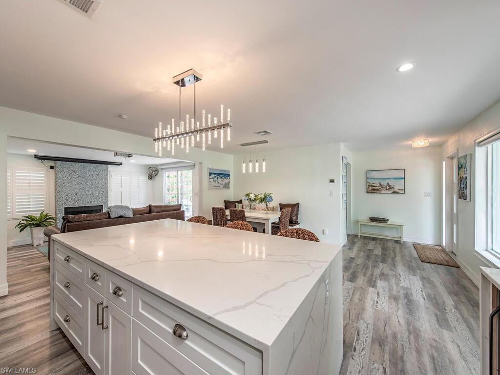 778 5th Avenue North Naples, FL 34102 - Photo 15 of 23 a large kitchen with kitchen island a stove a sink dishwasher and a dining table with wooden floor