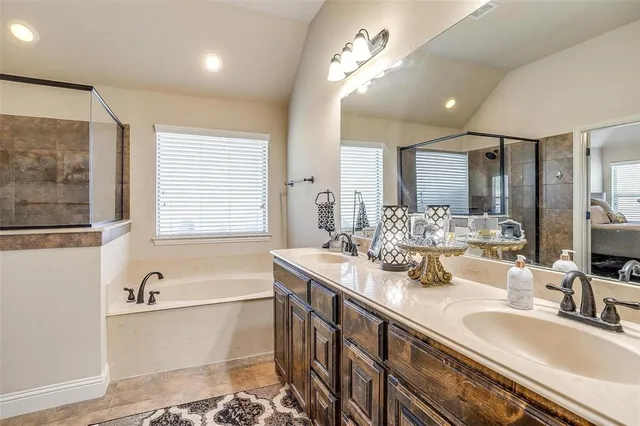 a bathroom with double vanity sinks a large mirror and a bathtub