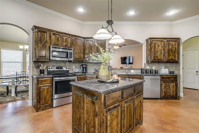 a kitchen with stainless steel appliances granite countertop a stove a sink a refrigerator and a microwave