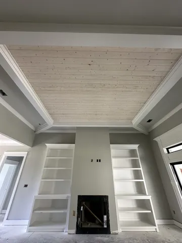 an empty room with windows and fireplace