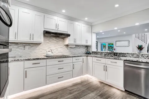 a kitchen with granite countertop white cabinets and white stainless steel appliances