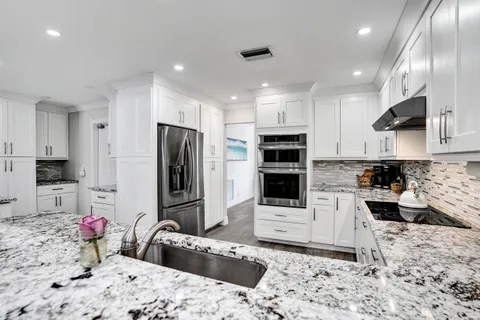 a kitchen with stainless steel appliances kitchen island granite countertop a refrigerator and a stove top oven