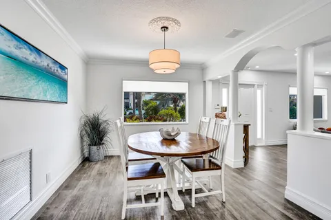 a dining room with wooden floor a chandelier a wooden table and chairs