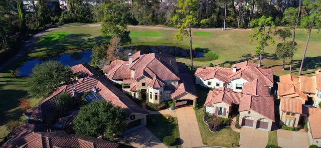 an aerial view of a house with outdoor space and trees all around