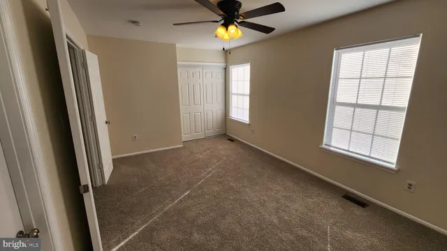 an empty room with windows and fan