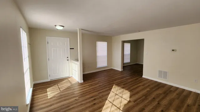 a view of an empty room with wooden floor and closet