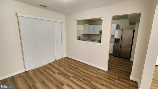 a view of a hallway with wooden floor and a bathroom