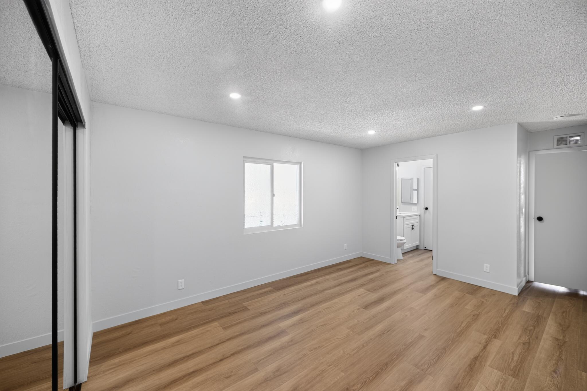15181 Van Buren Boulevard, Unit 102 Riverside, CA 92504 - Photo 17 of 29 an empty room with wooden floor and windows