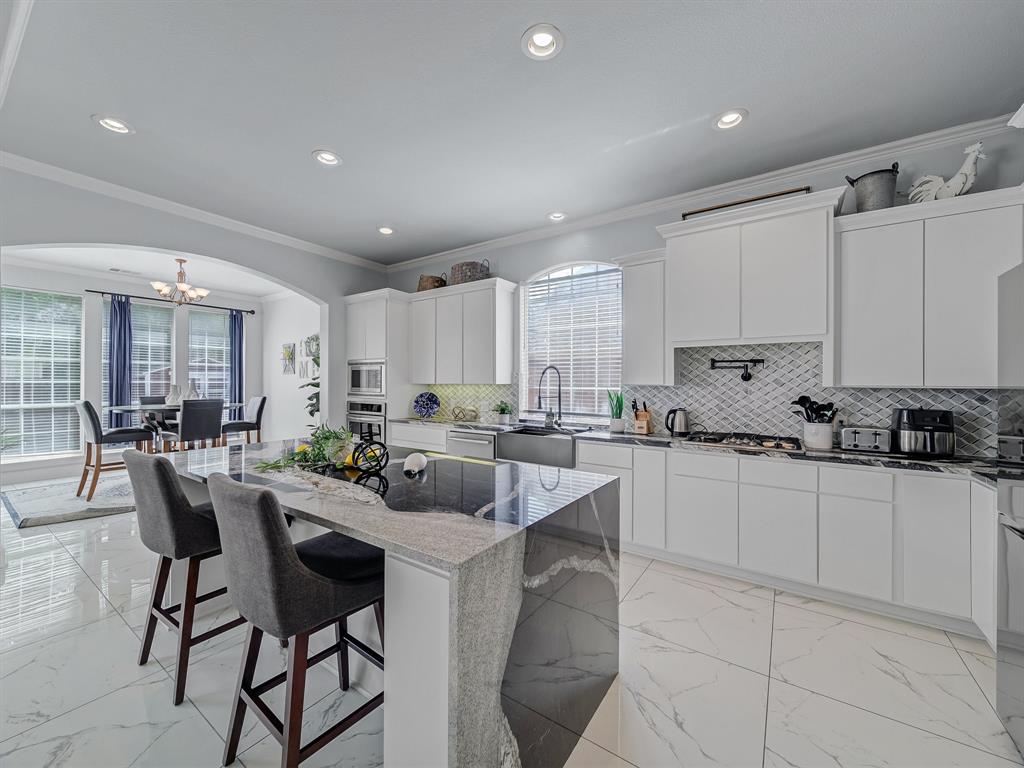 4332 Millsop Drive Carrollton, TX 75010 - Photo 16 of 37 a kitchen with white cabinets a sink a stove a dining table and chairs