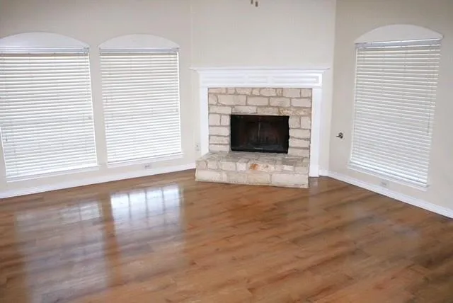 an empty room with wooden floor and fireplace