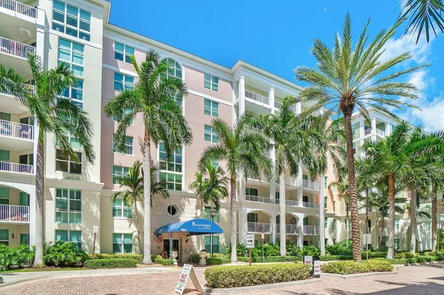 a front view of a multi story building with yard and green space