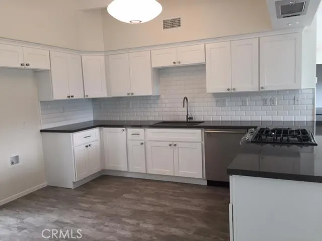 a kitchen with white cabinets and appliances