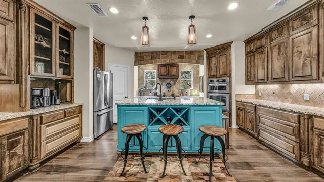 a kitchen with stainless steel appliances kitchen island granite countertop a refrigerator and cabinets