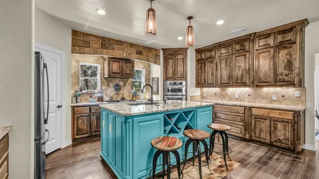 a kitchen with stainless steel appliances granite countertop a stove refrigerator and cabinets