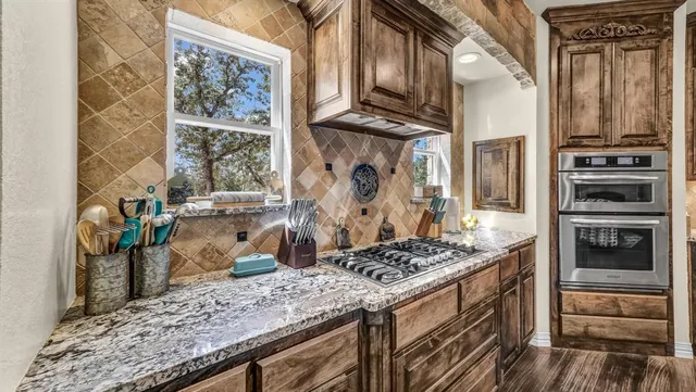 a kitchen with stainless steel appliances granite countertop a stove and a wooden cabinets