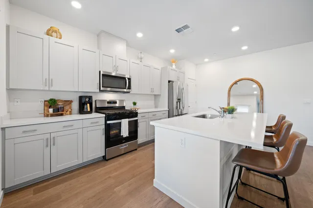 a kitchen with a sink white cabinets and black appliances