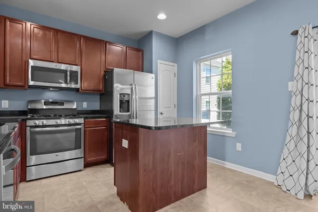 a kitchen with stainless steel appliances granite countertop a stove a refrigerator and a microwave
