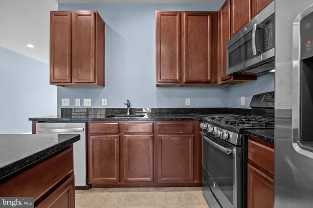 a kitchen with stainless steel appliances granite countertop a stove a sink and a microwave