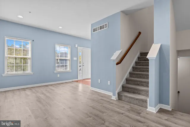 a view of an empty room with wooden floor and stairs