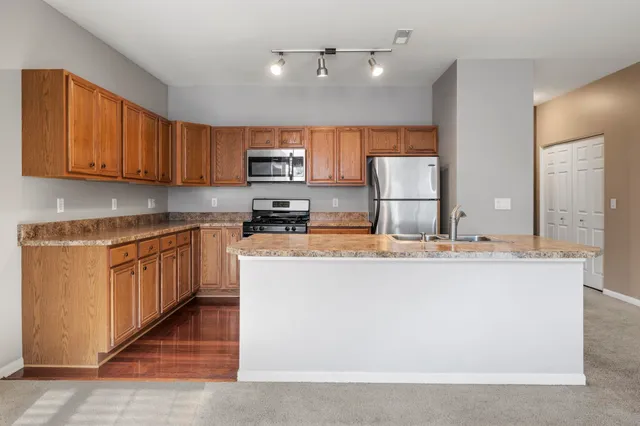 a kitchen with kitchen island granite countertop a stove top oven a sink a counter top space and cabinets