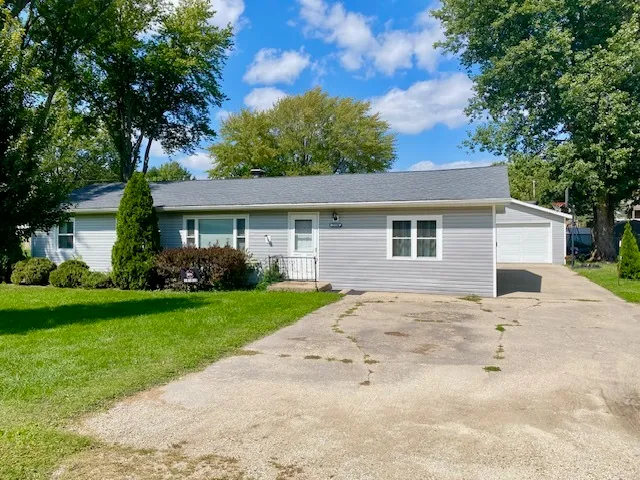 a view of a yard in front of a house with plants and large tree