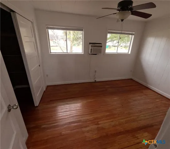 a view of an empty room with wooden floor and a window