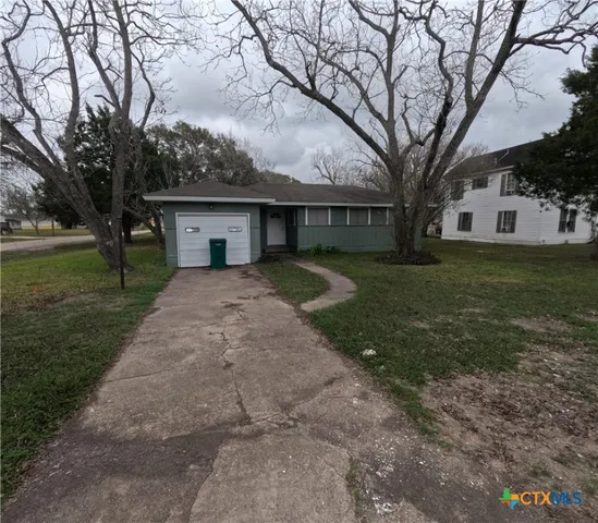 a front view of a house with a yard and trees