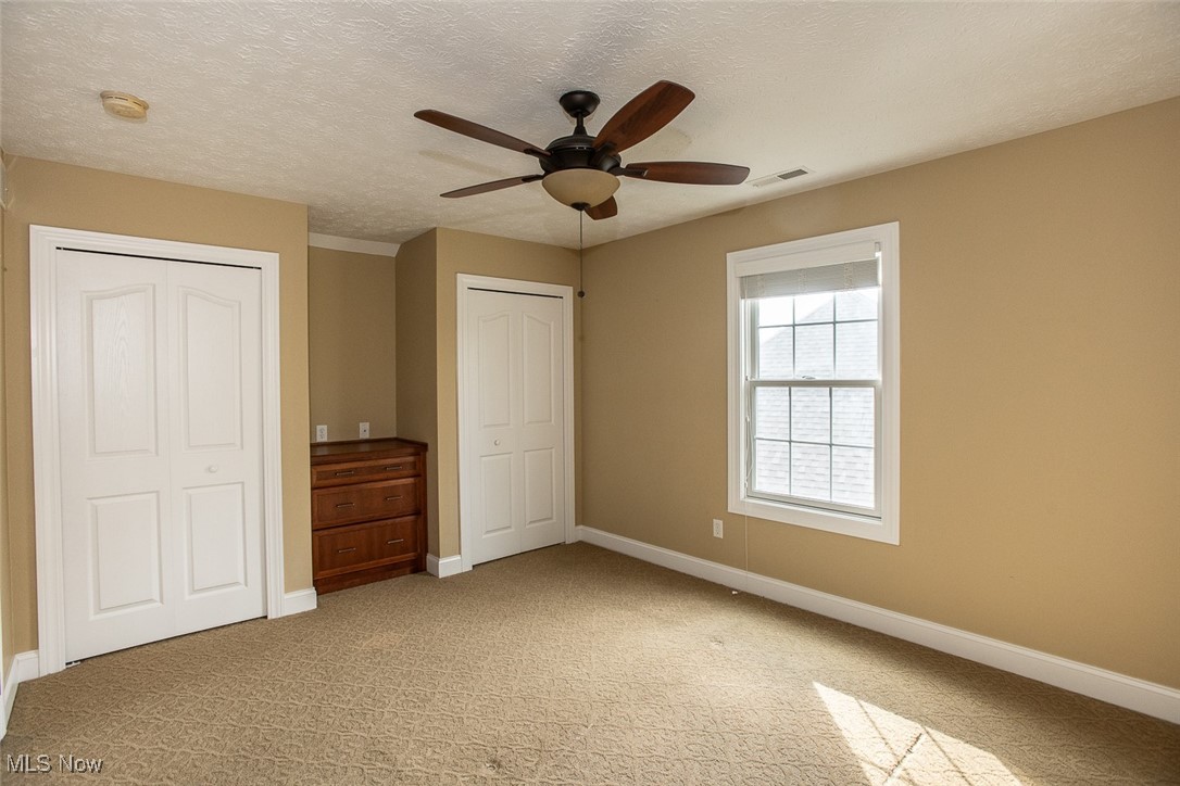 630 Rundle Street Lagrange, OH 44050 - Photo 29 of 49 Unfurnished bedroom featuring a textured ceiling, light colored carpet, multiple closets, and ceiling fan