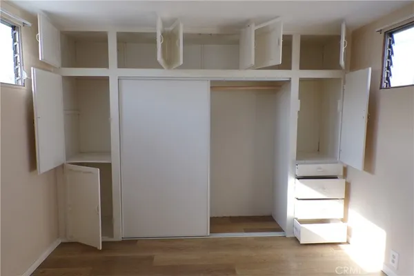a view of an empty room with wooden floor and cabinet